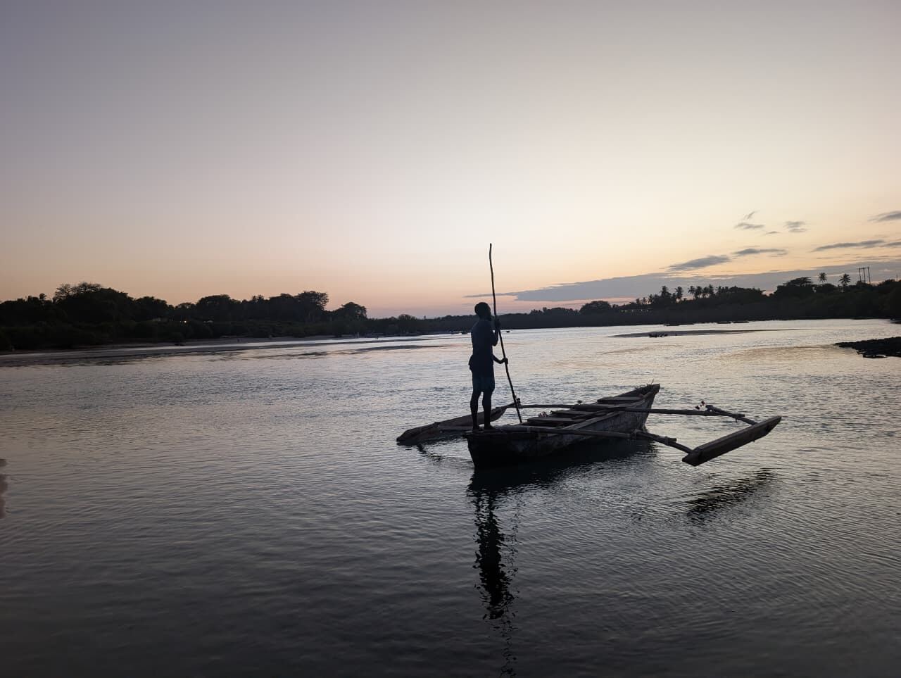 Guide paddling a traditional canoe at dusk on the Kongo River