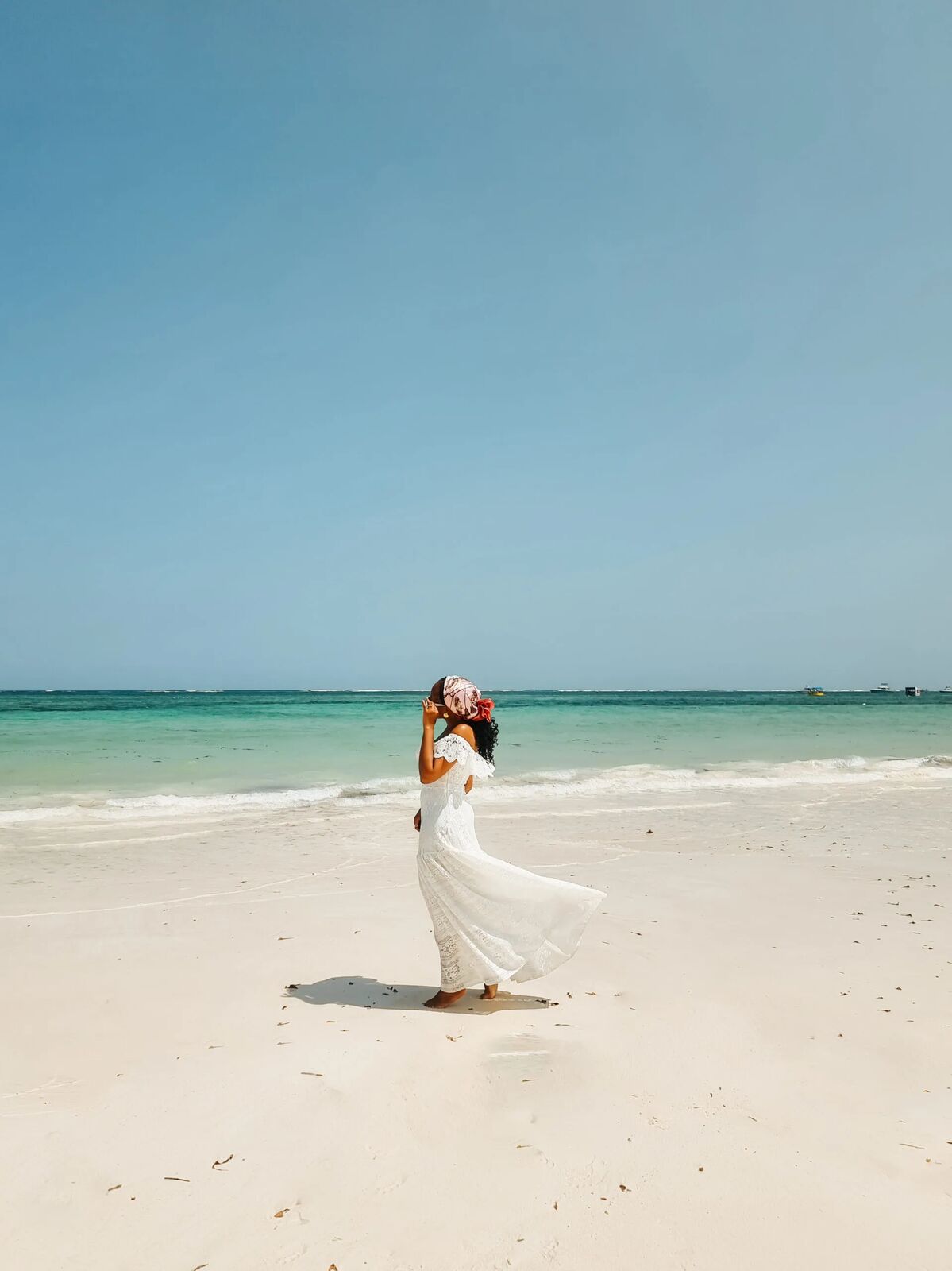 Traveller in a flowing white dress walking along Diani Beach